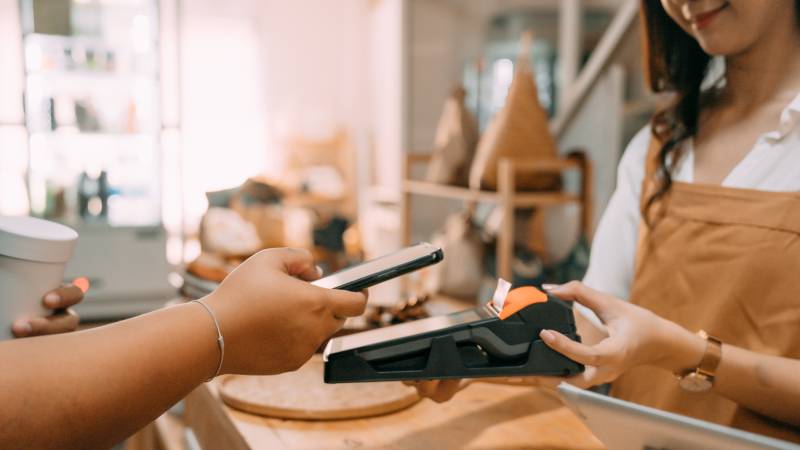 person paying with phone on contactless payment terminal