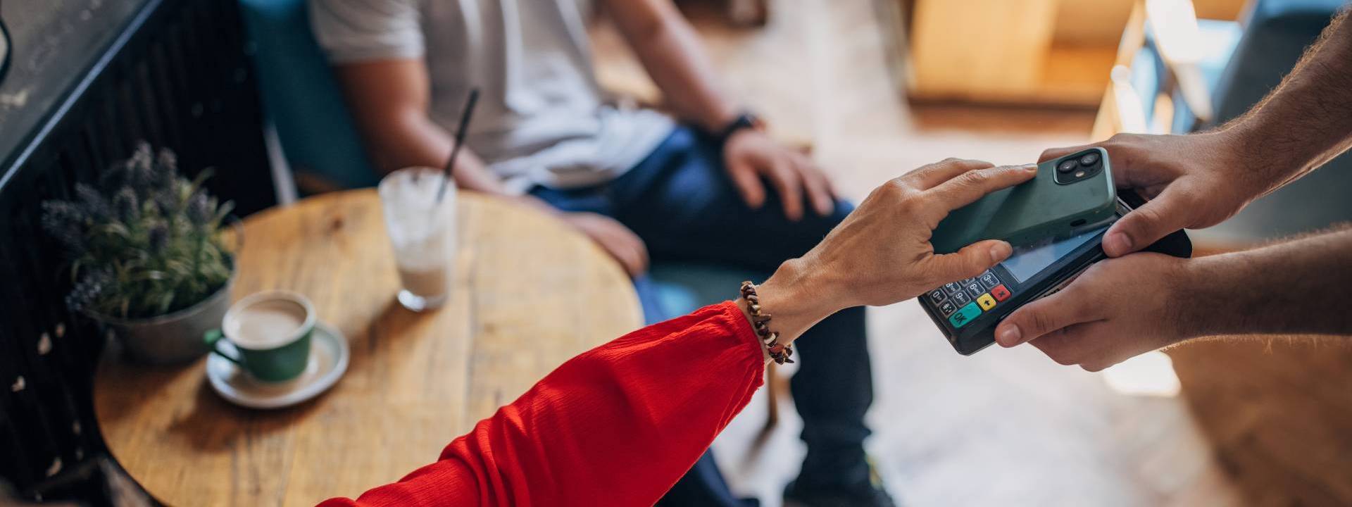 woman paying contactless with mobile on a coffee shop