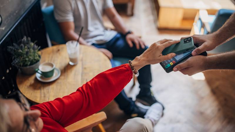 woman paying contactless with mobile on a coffee shop